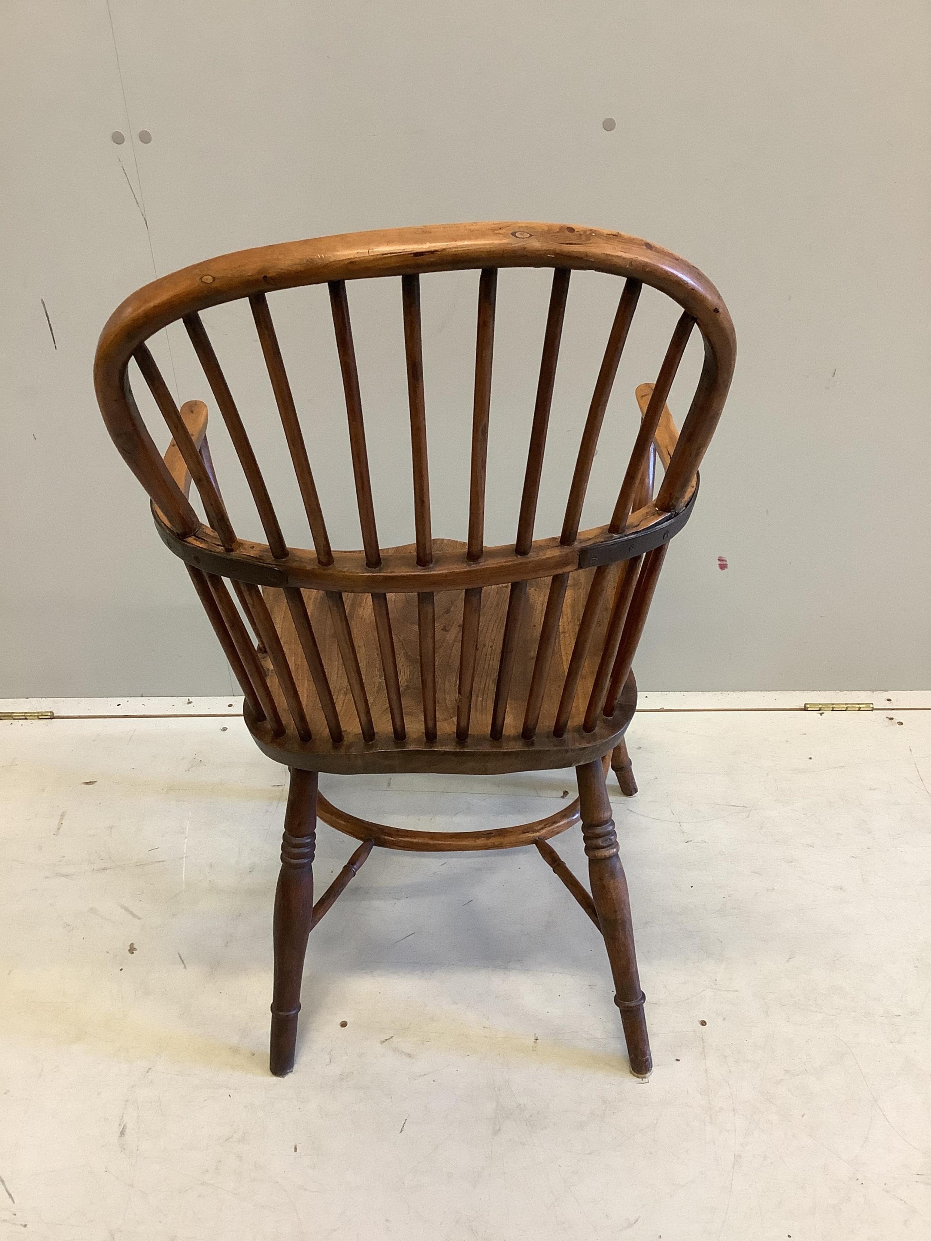 An early 19th century yew and elm comb back Windsor elbow chair with crinoline stretcher, width 53cm, depth 42cm, height 99cm. Condition fair, arm rail split to left side, left leg now misshapen with minor chips.